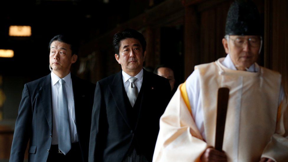 Japan"s Prime Minister Shinzo Abe (C) is led by a Shinto priest as he visits Yasukuni shrine in Tokyo December 26, 2013