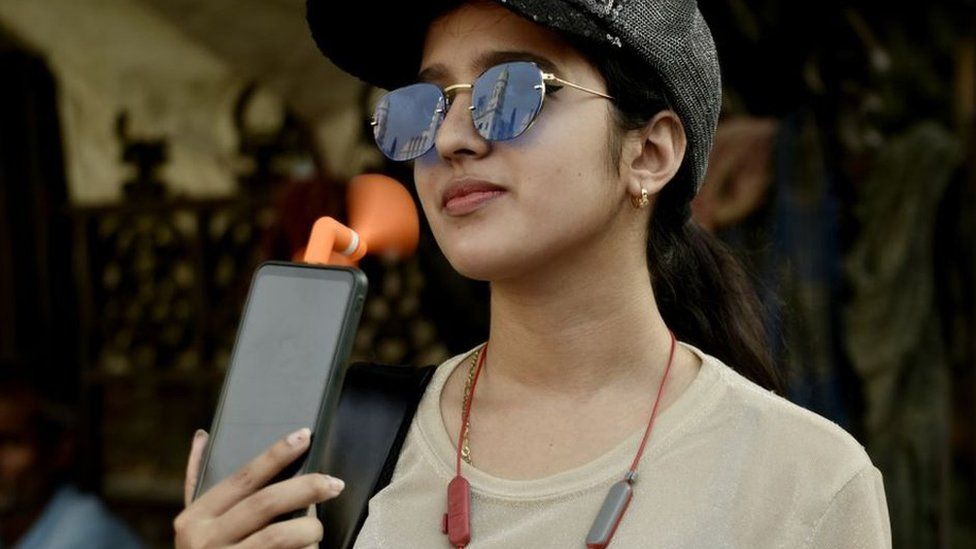 A girl holds a portable mobile connected fan amid heatwave in Kolkata, India, 27 April, 2022.