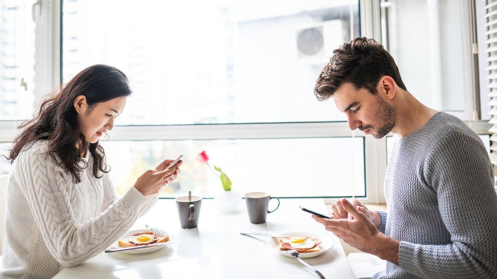 Couple drink tea as they look at their phones