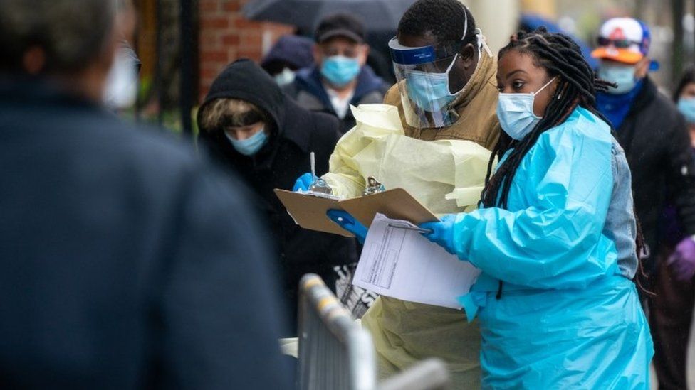 Medical workers assist people standing in line at NYC Health + Hospitals/Gotham Health, Gouverneur waiting to be tested for the coronavirus (COVID-19) on April 24, 2020, in New York City.