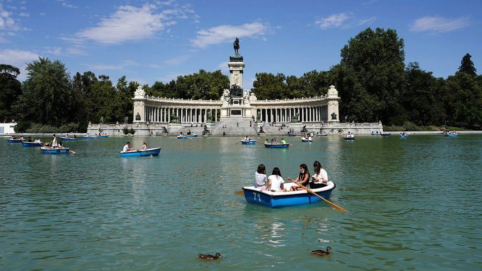 Люди наслаждаются прогулкой на лодке по озеру в парке Ретиро в Мадриде, Испания, 25 июля 2021 г.
