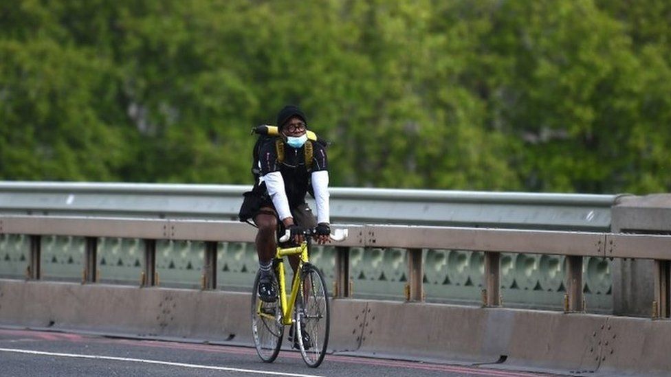 A cyclist wearing a protective mask crosses Westminster Bridge on 7 May, 2020 in London