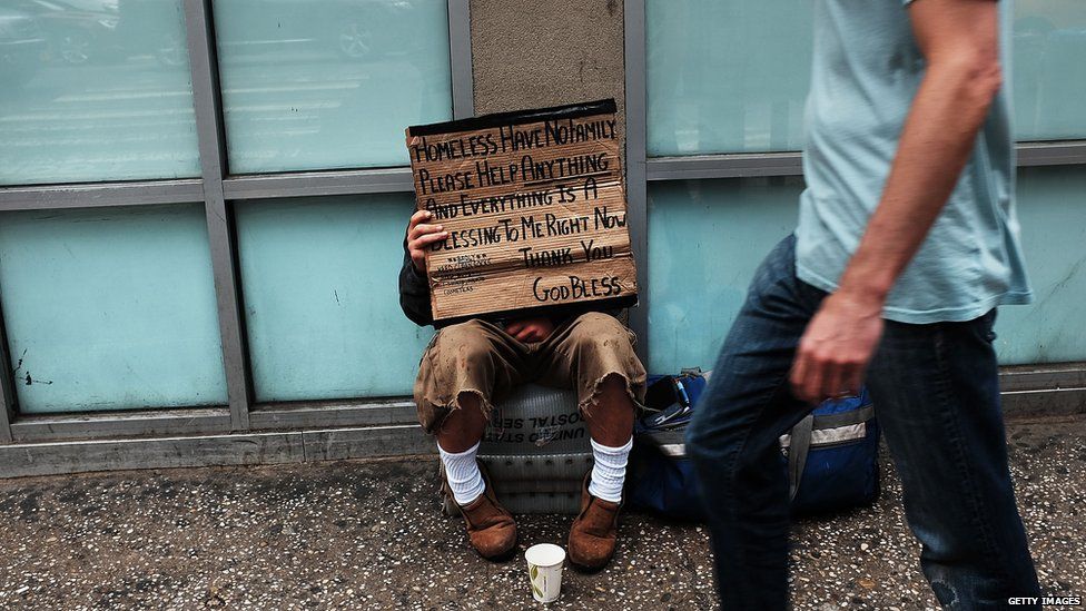 A homeless man panhandles along Eighth Avenue in Manhattan on 18 May 2015 in New York