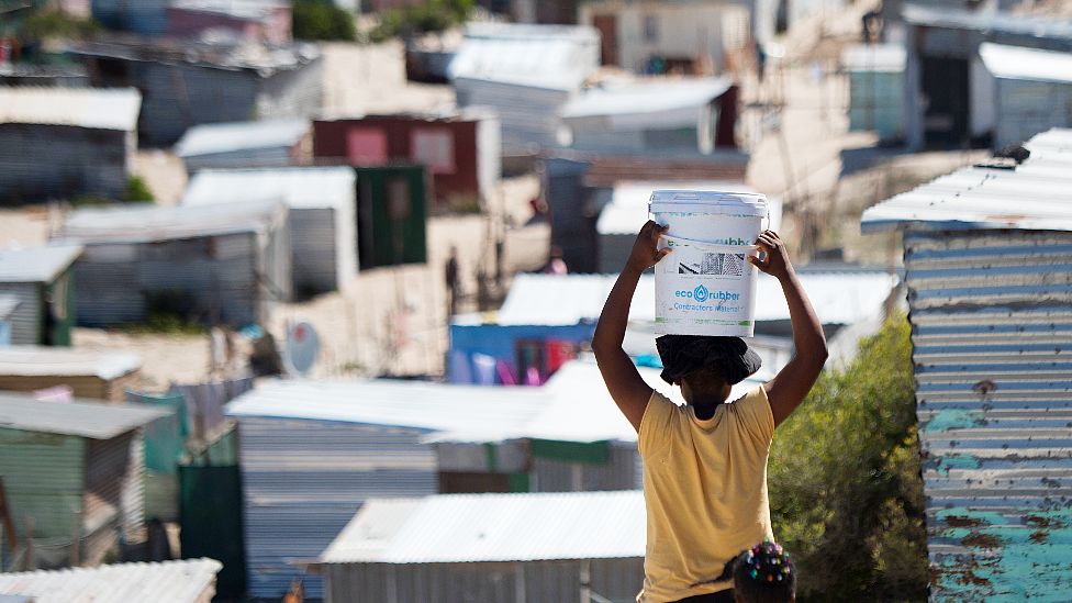 A woman carrying a bucket of fresh water to an informal settlement in Khayelitsha, near Cape Town- 31 March 2020