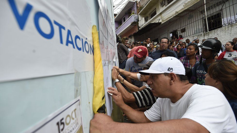 Image shows voters looking for their names in an electoral roll during the elections for state governors in Venezuela on 15 October 2017
