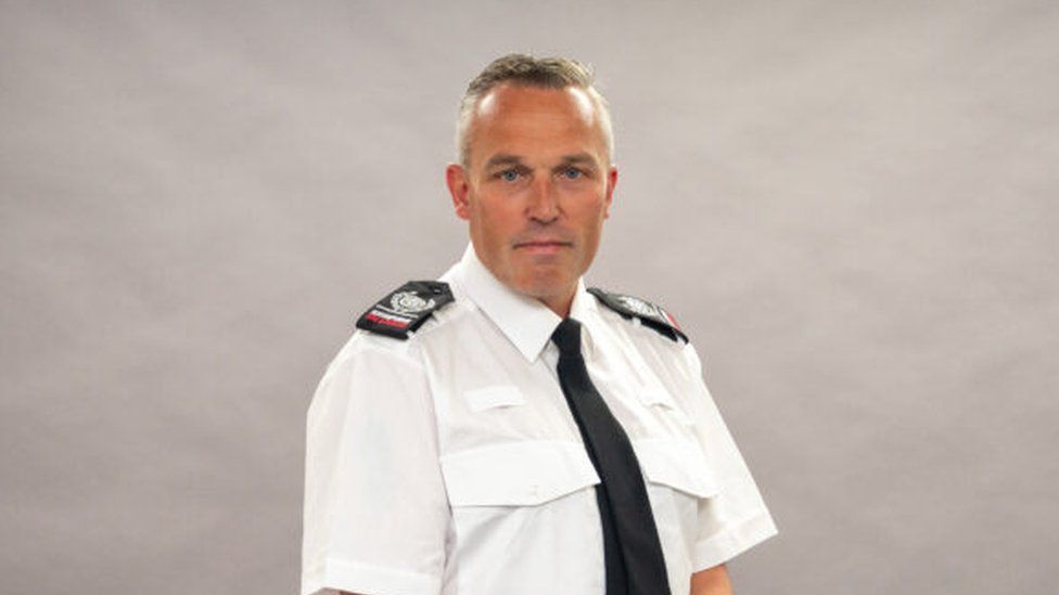 Man with short hair wearing a fire officer's uniform against a neutral background