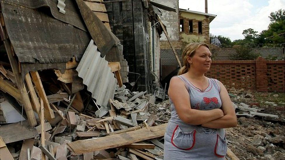 A woman stands near of her damaged home in the pro-Russian rebel-controlled city of Horlivka