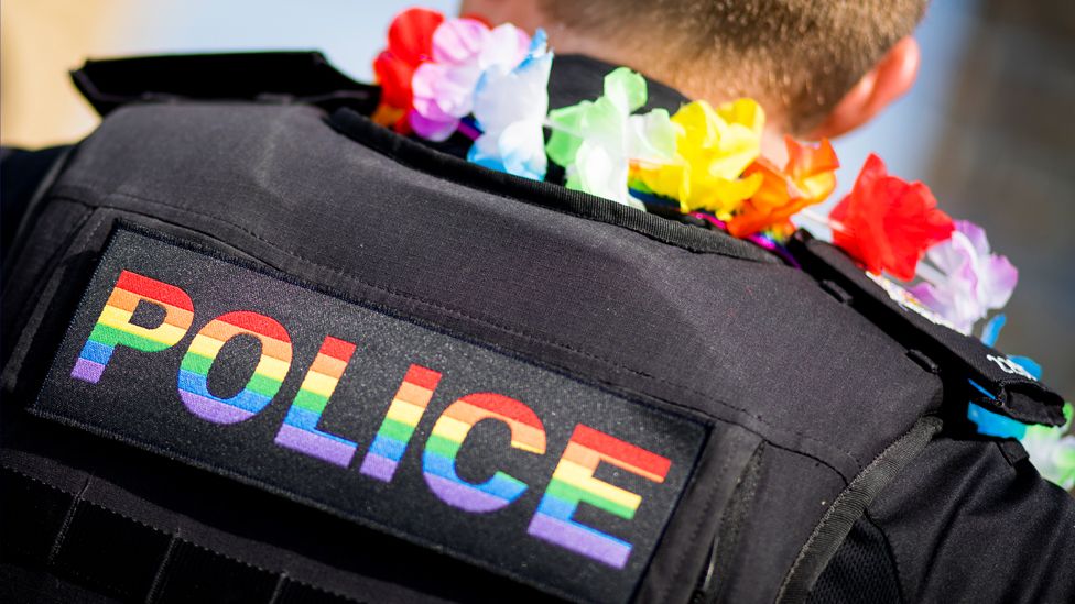 Policeman with 'Police' written on his back in the colours of the LGBTQ flag