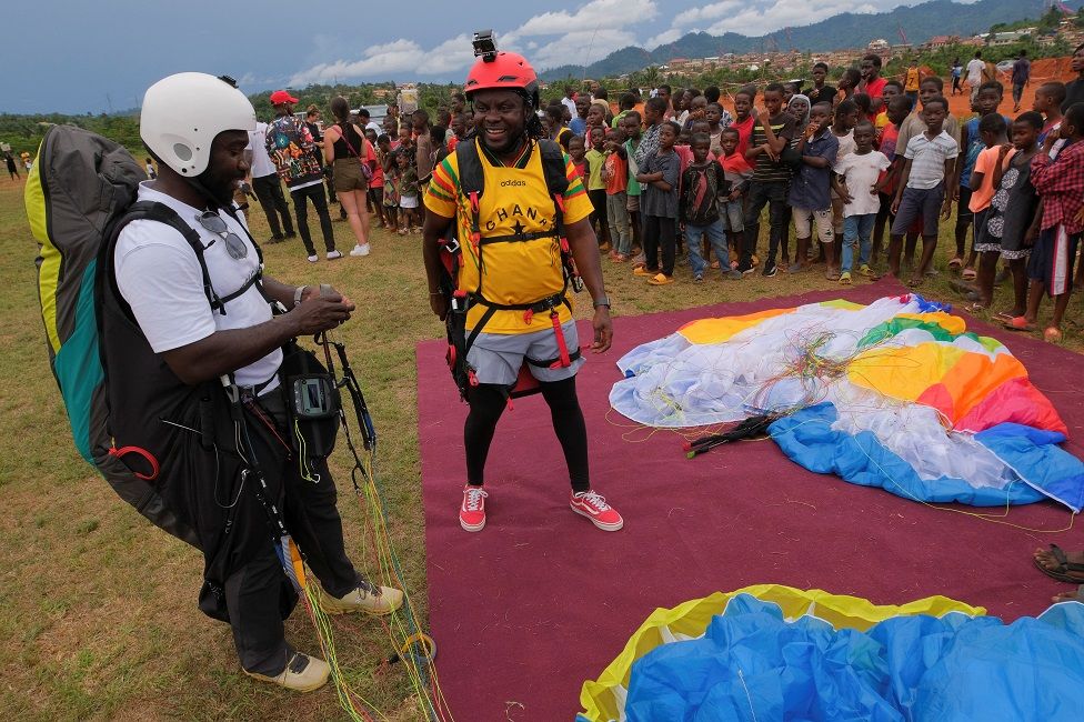 People watch as Ghanaian paragliders Michael Kwakye and Stephen Asamoah land at the Nkawkaw football field.