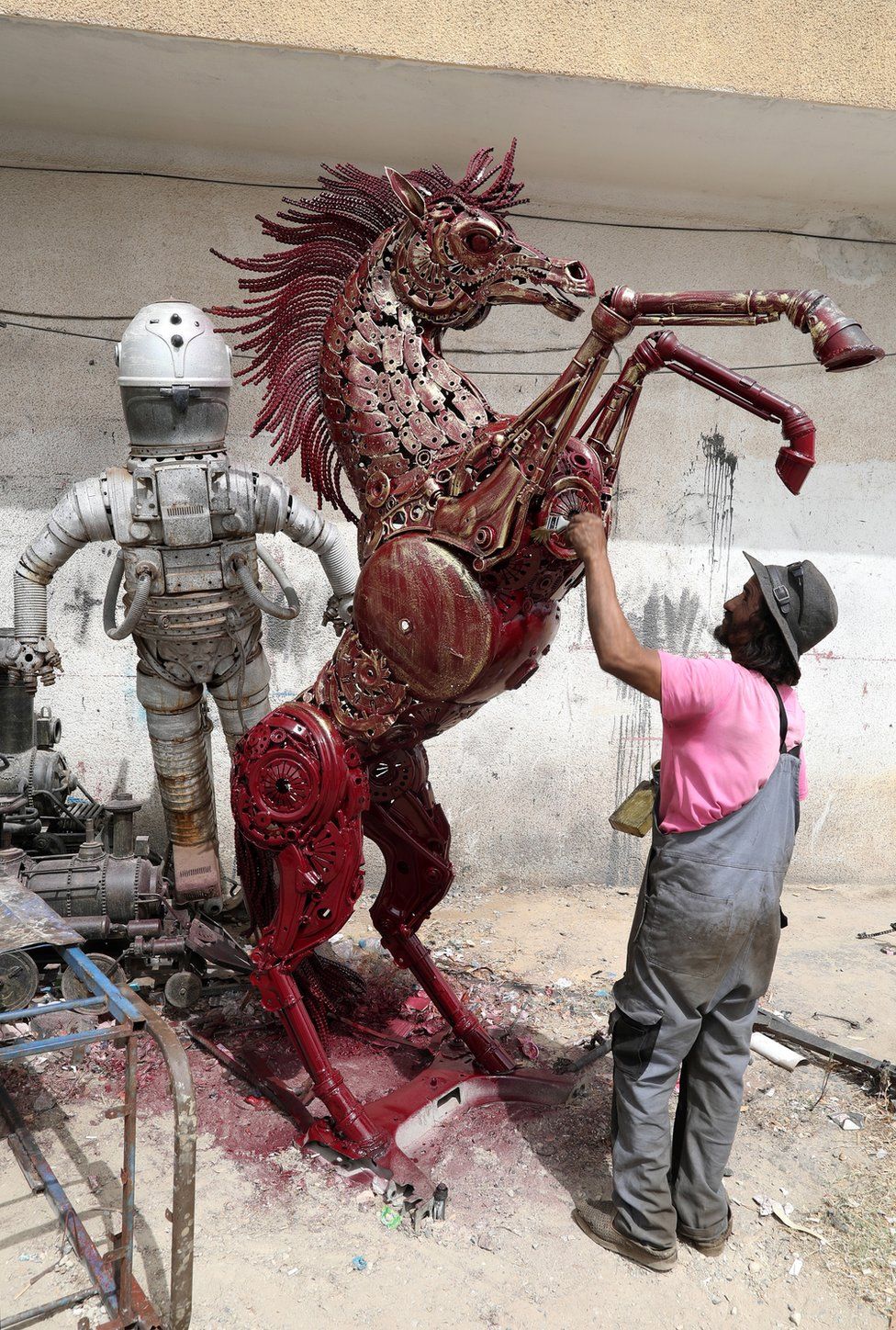 A man works on a metal sculpture of a horse.