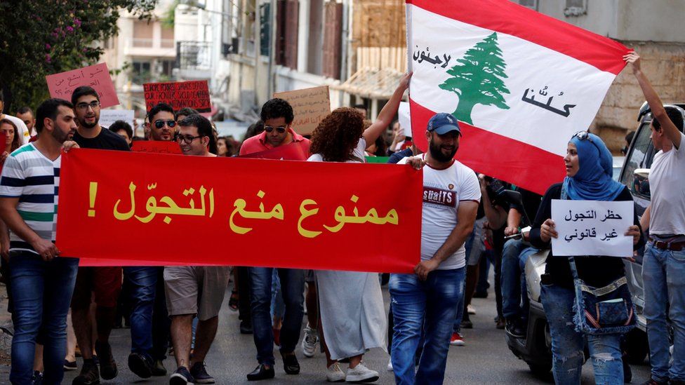 People attend a demonstration against curfews imposed on Syrian refugees in Beirut, Lebanon. The banners read (L to R) in Arabic, "Curfews are not allowed", "We are all refugees" and "Curfews are illegal" (18 July 2016)