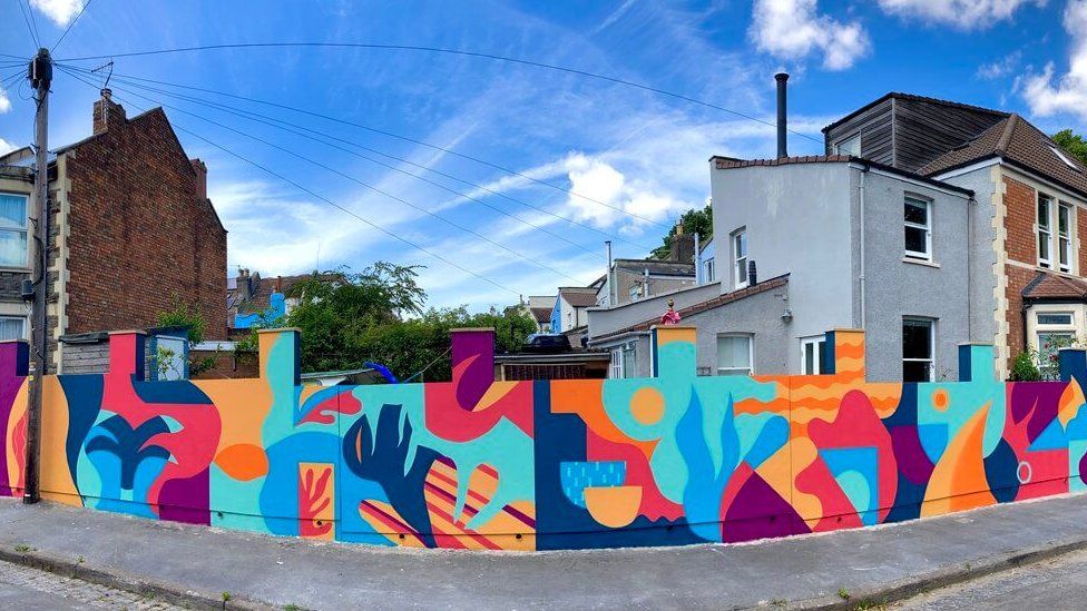 A mural painted on a wall with turquoise, purple and orange features shapes