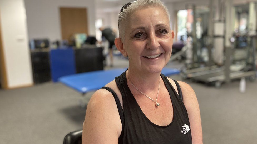 Karen Perrins smiling as she sits in a gym