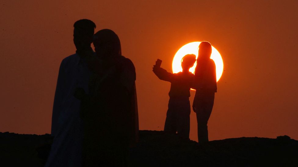 People taking selfies as the sun rises in Abu Sir, Egypt - Wednesday 10 April 2024