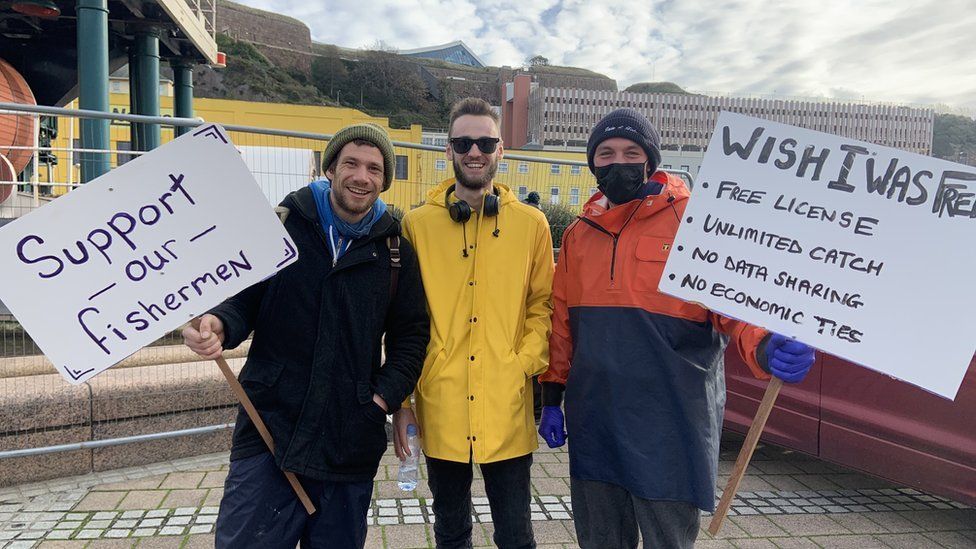Three fishermen with signs protesting post-Brexit fishing rows