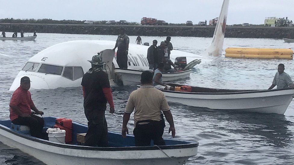 People in small boats around the plane in the water