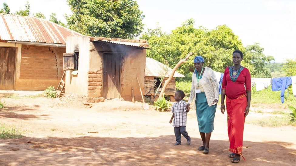 A traditional birth attendant walks with a pregnant mother