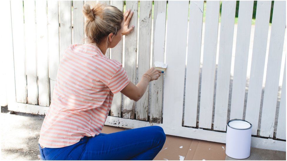 Woman painting a fence