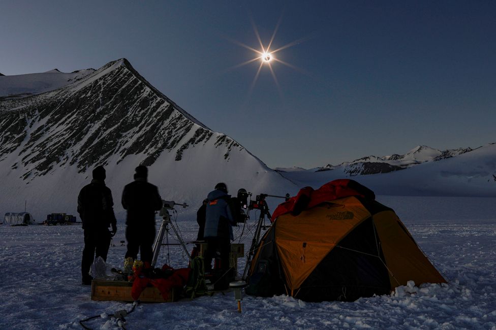 People observe a solar eclipse from "Glaciar Union", the scientific polar station in Antarctic, on Chilean territory on 4 December 2021.
