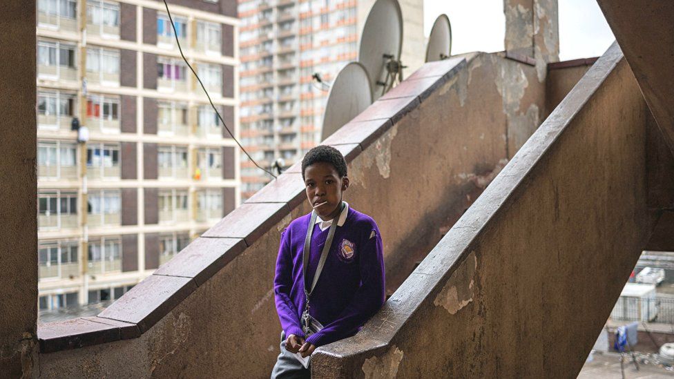 Ребенок спускается по лестнице захваченного здания в Верии, Йоханнесбург, Южная Африка – май 2023 г.