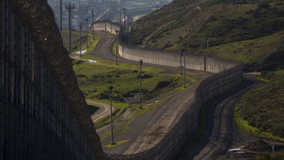 The existing barricade - made of steel wall, fences, and razor wire - is seen winding along the US-Mexico border in San Ysidro, California.