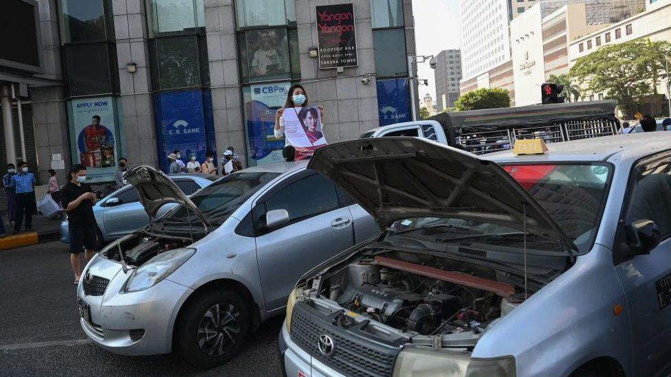 Автомобили с открытыми капотами припаркованы, чтобы перекрыть дорогу во время демонстрации против военного переворота в Янгоне 17 февраля 2021 года