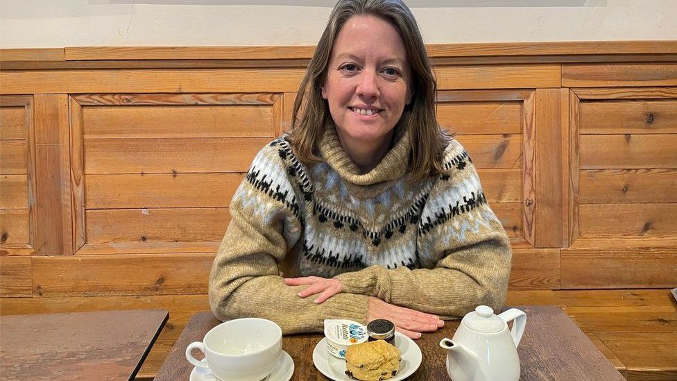 Sarah Merker sits in a National Trust cafe with a scone and pot of tea