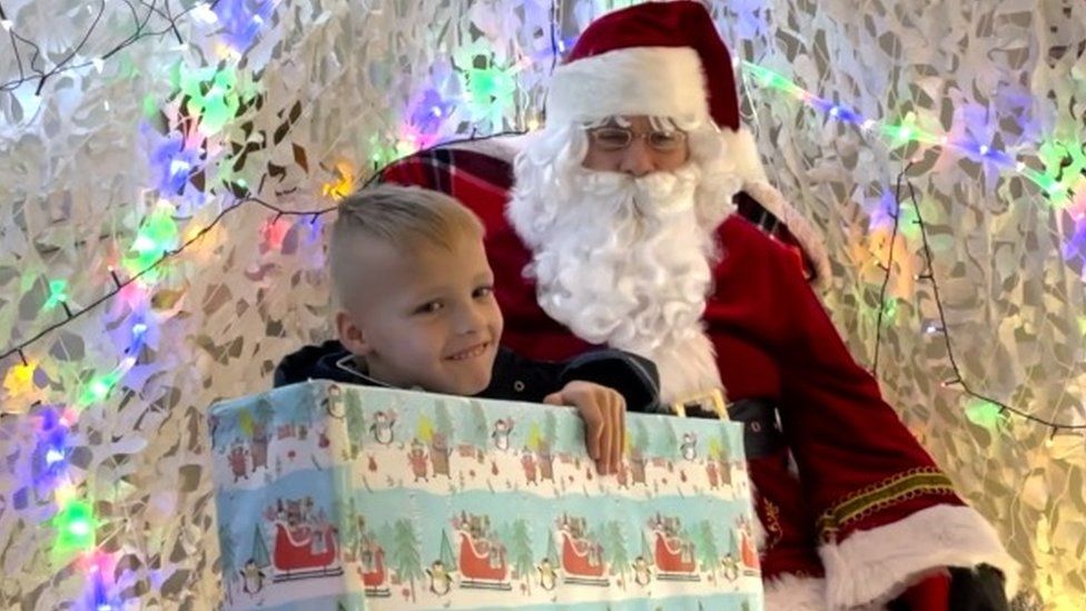 A little boy receives a gift in Santa's grotto