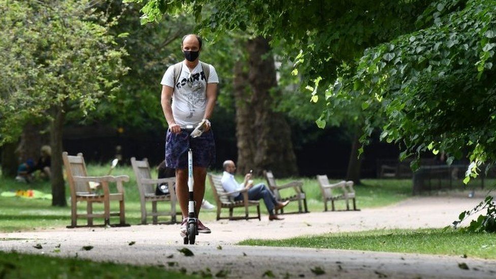 A man rides an electric scooter through St James' Park in central London