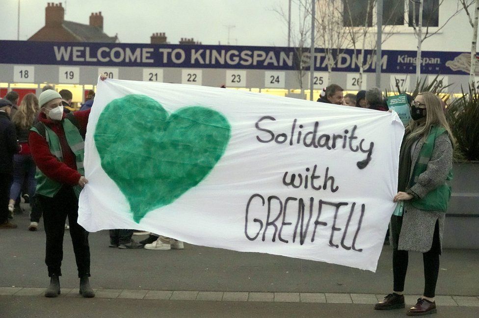 People standing outside Ulster Rugby's Kingspan Stadium, holding a banner that reads: Solidarity with Grenfell