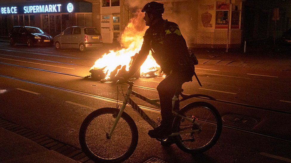A police officer rides near a burning bin in The Hague, Netherlands