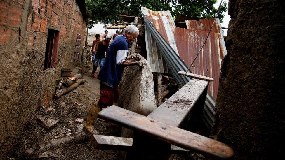 A man tries to carry mattress following floods due to heavy rains, in Las Tejerias, Aragua state, Venezuela October 9, 2022.