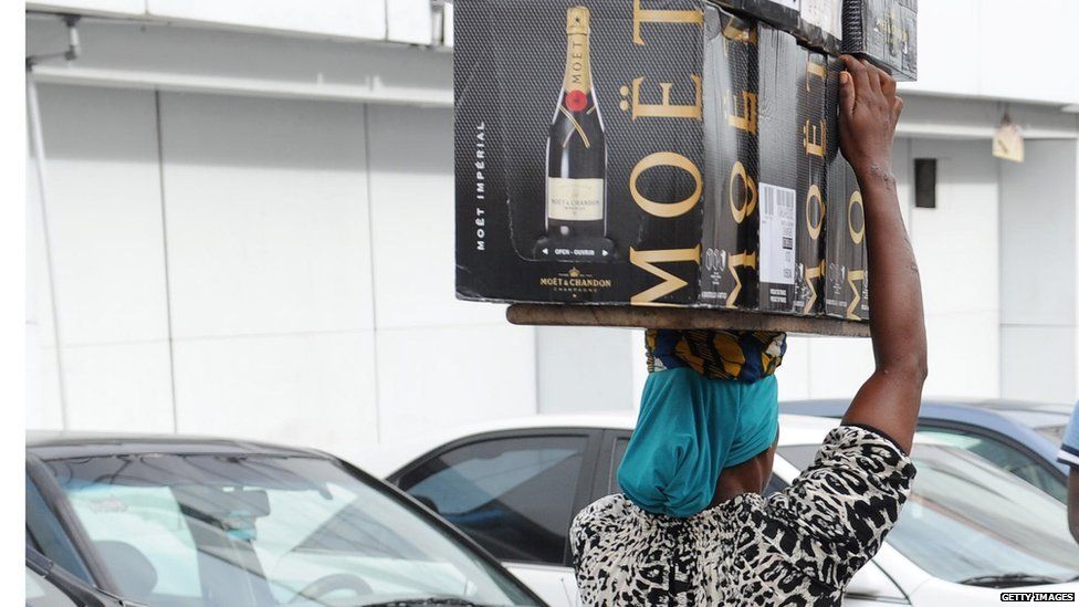 A delivery woman carries cases of champagne in Lagos on April 23, 2013.