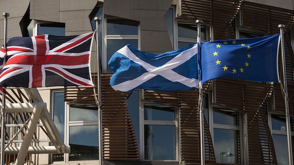 A Scottish Saltire (C) flies between a Union flag (L) and a European Union (EU) flag in front of the Scottish Parliament building in Edinburgh