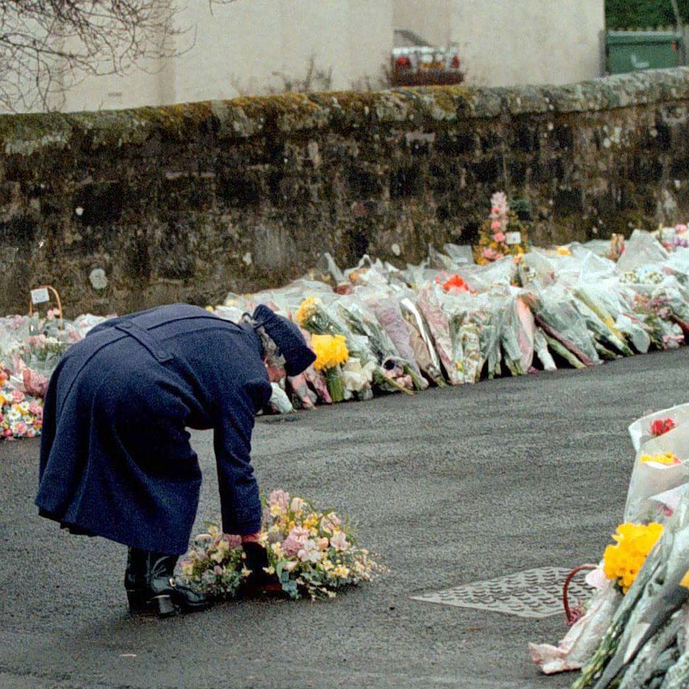 Queen Elizabeth II laying a wreath at the gates of Dunblane Primary School after one of the deadliest firearms incidents in UK history.