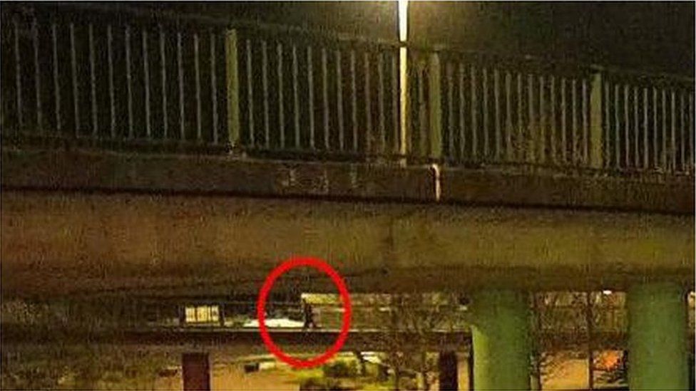 CCTV from Bennett Way on the north side of the River Avon in Bristol the night Jack O'Sullivan was last seen. It is dark but a figure, circled in red, can be seen walking over the bridge, which is lit by streetlights. The bridge crosses a road and is made of concrete, with metal railings on either side of the path