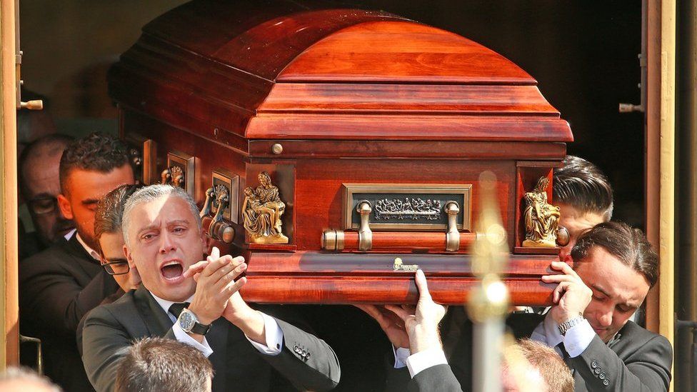 Joseph "Pino" Acquaro's brother Massimo applauds as he and fellow pallbearers carry the coffin from St Mary's Star of Sea Catholic Church