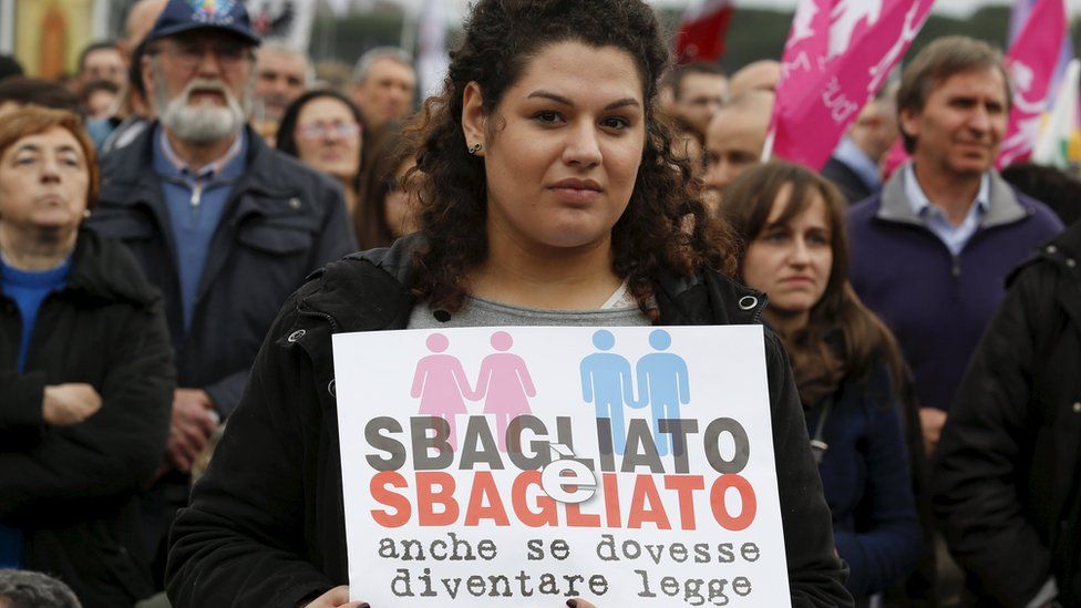 A woman attends a rally against same-sex unions holds a sign reading "it is wrong even if it becomes law"