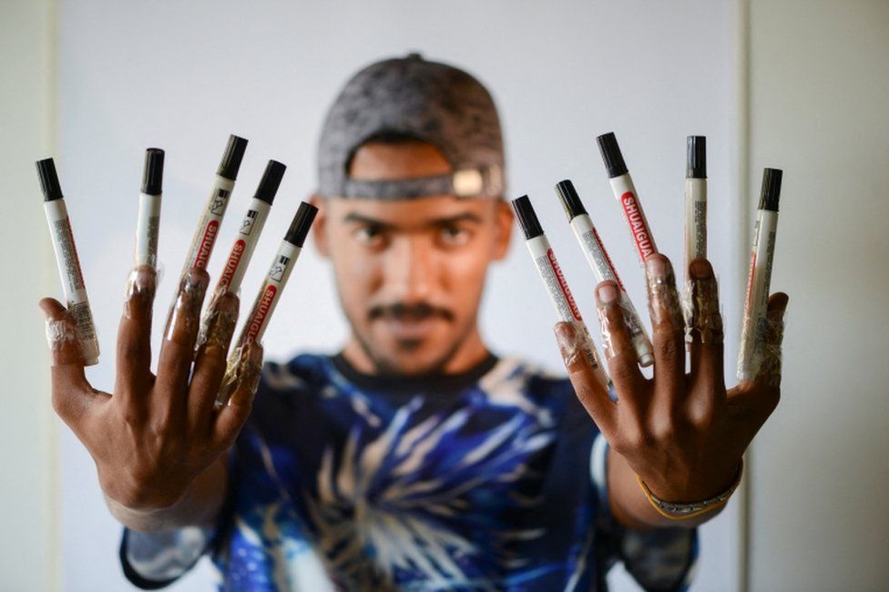 Artist Mohammed Mahmoud (Amedo), 27, tapes markers on his hands at studio in Benghazi.