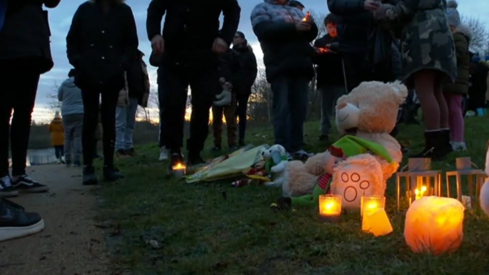 People stood next to teddy and candles