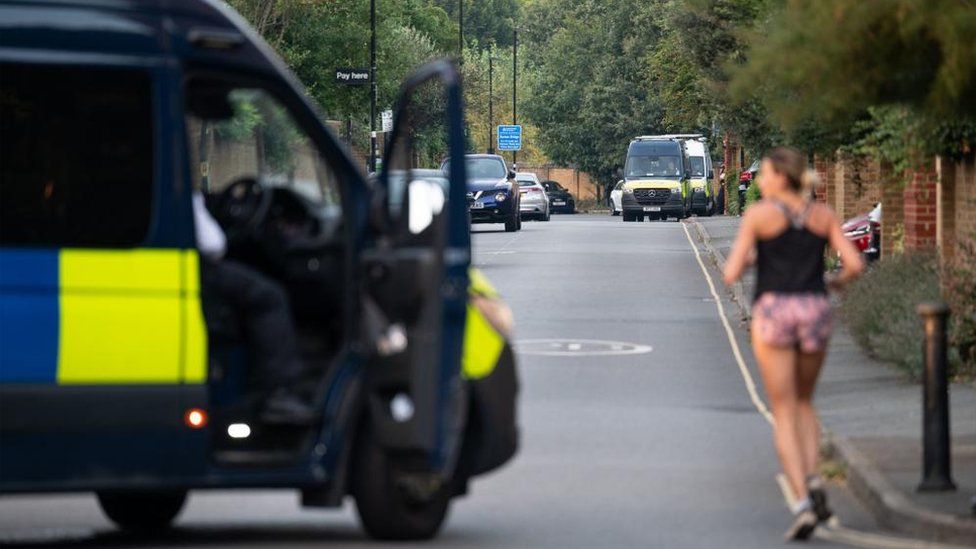 Police vans in Chiswick as a woman goes for a morning run