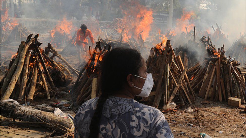 A family member looks on as several funeral pyres of COVID-19 victims burn during the mass cremation at Ghazipur cremation ground in New Delhi on 26 April 2021.