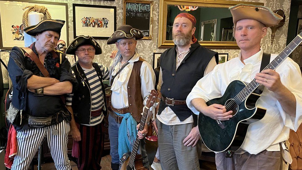 Members of Bristol pirate band Piratitude face the camera holding their instruments before playing a concert
