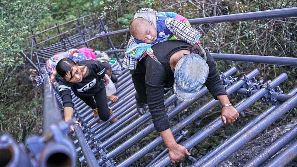 People climb on the newly-built metal ladder with hand railings to Ahtuler village on a cliff on November 11, 2016