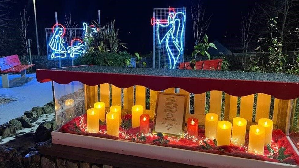 A cabinet with 10 candles representing the lives lost in October's blast sits amongst Creeslough's Christmas display
