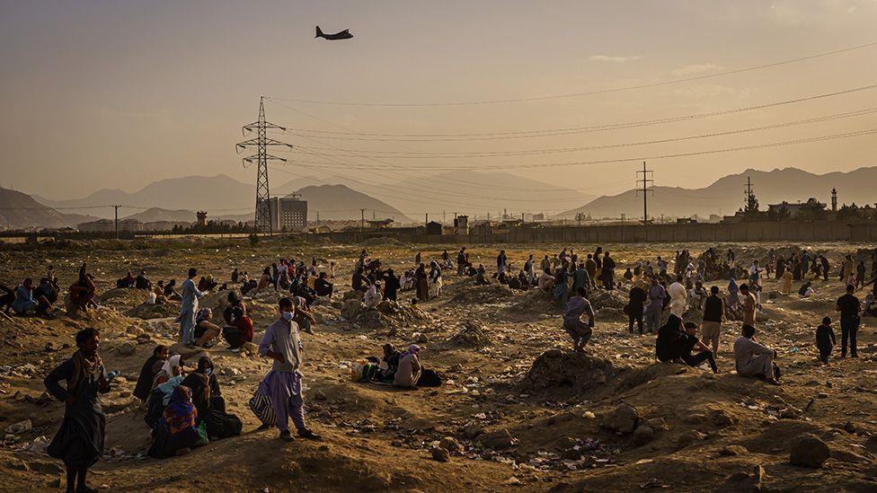 A military transport plane takes off as Afghans who cannot get into the airport to evacuate, watch and wonder while stranded outside, in Kabul, Afghanistan - 23 August 2021