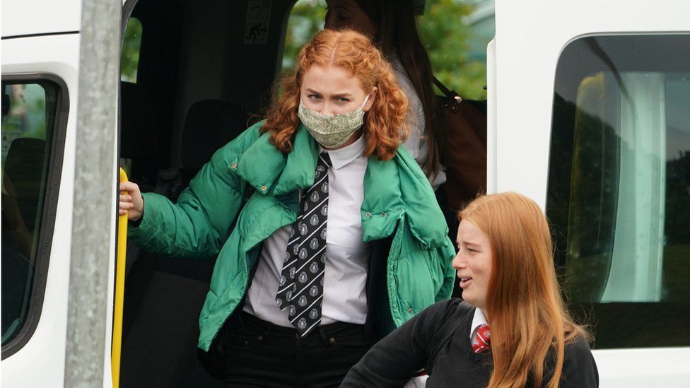 A pupil wears a face covering getting off a school bus in Scotland