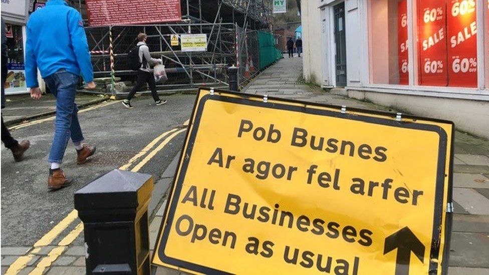 A road sign on the street saying businesses are still open