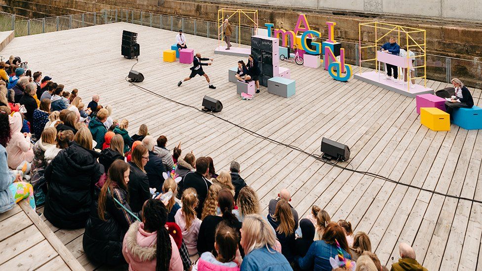 People sitting at an open air auditorium watching a play
