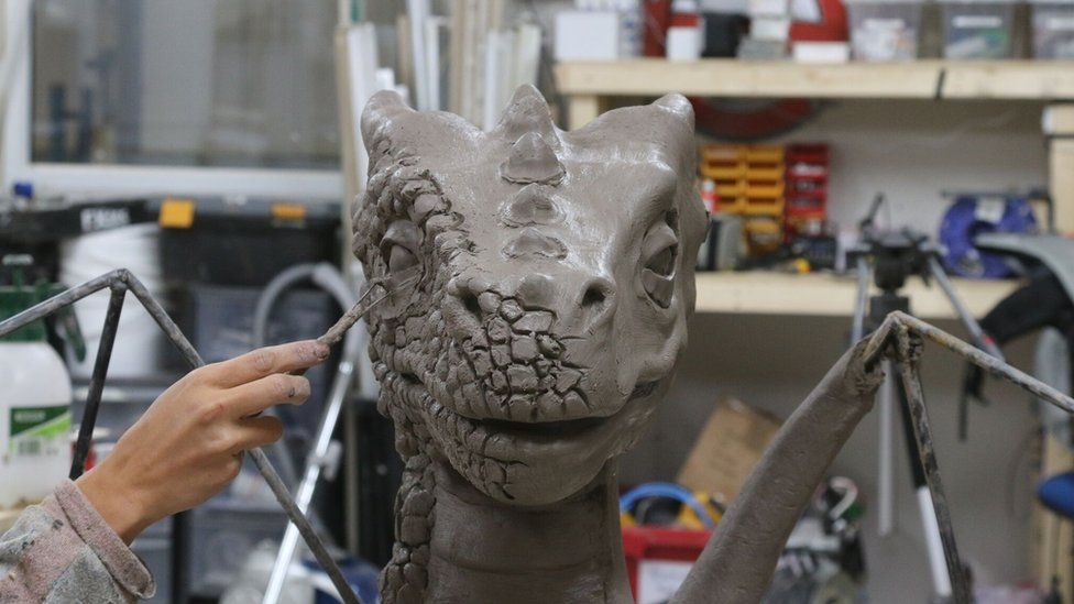An artist working on a dragon sculpture